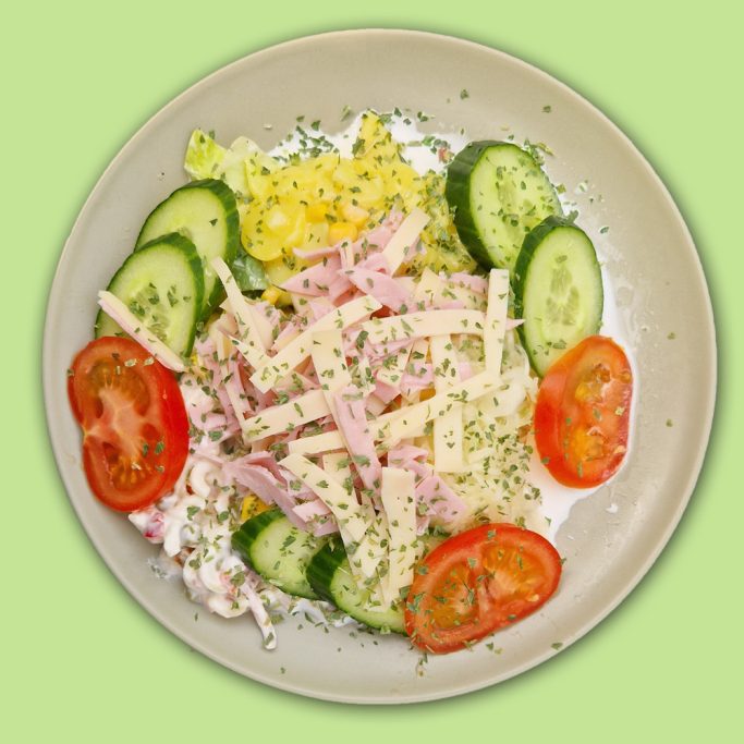 Kartoffelsalat mit Wurst- und Käsestreifen garniert mit Gurken und Tomaten